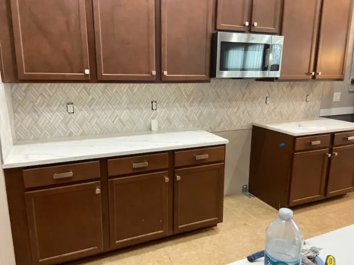 kitchen remodel featuring medium-toned wood cabinets and white quartz countertops with a herringbone-patterned backsplash
